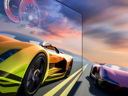 Sportovní žlutý a černý automobil v popředí na silnici, červený a černý sportovní automobil v pozadí, oblačná obloha