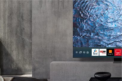 Samsung højopløsnings-tv F-TQ77S95D-BF, delvist synlig skærm, grå væg, lavt møbel, sort vase