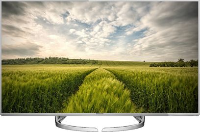 Panasonic TX-58DX750F-fladskærm viser et grønt hvedemark under en skyet himmel, smal sølvramme, centralt fod