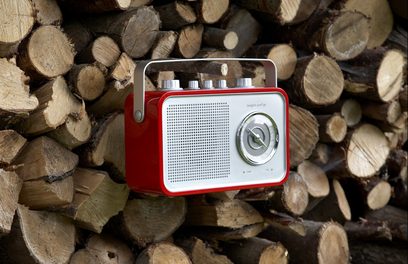 Rød bærbar Tangent Uno 2Go-radio placeret på en bunke træstammer, set forfra i nærbillede