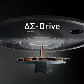 Vista en picado de un mecanismo circular negro de metal y plástico, bobina de cobre y eje central, texto "ΔΣ-Drive"