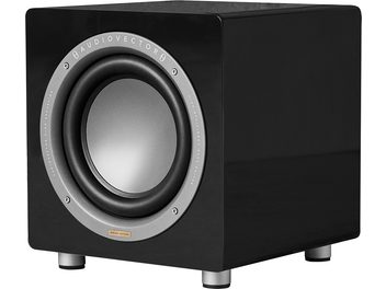 AudioVector QR Sub SE subwoofer i sort, kubisk sort højglanslakeret kabinet med en grå, cirkulær højttaler omkranset af en sølvfarvet metalring med mærkets logo, monteret på fire cylindriske fødder, set fra venstre forreste hjørne