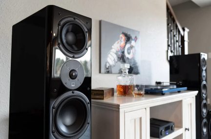 Sort højttaler med 3 højttalere, hvidt møbel med karaffel og glas, pladespiller, maleri, trappe