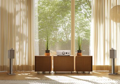 Integrert stereo hi-fi forsterker Denon PMA-3000NE sølv på tremøbel, 2 grå høyttalere, 2 potteplanter, beige gardiner