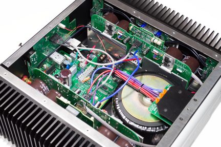Hi-fi stiprintuvo vidus su toroidiniu transformatoriumi, žaliomis elektronikos plokštėmis ir įvairiaspalve instaliacija