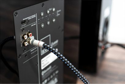 Kabel for subwoofer SoundPath Subwoofer 1m koblet til baksiden av en svart lydanordning med RCA-kontakter