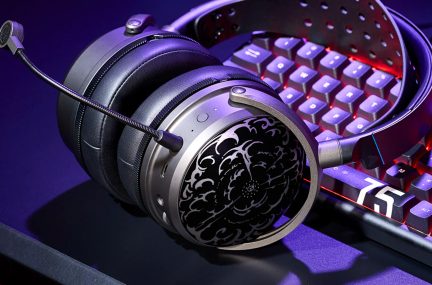 Black gaming headset with headband, boom microphone, and round earcups, placed in front of a red and purple backlit keyboard