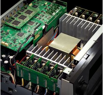 Innenansicht eines schwarzen Denon AVR-4520 Verstärkers mit grünen Leiterplatten, Kühlkörpern und elektronischen Bauteilen