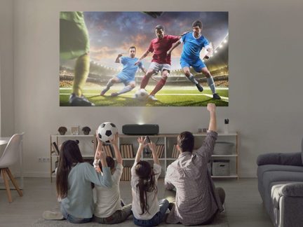 Tre fodboldspillere i aktion på en bane og en familie, der ser en fodboldkamp i fjernsynet i en stue