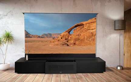 Proyector de vídeo de ultracorta distancia sobre mueble de TV negro, gran pantalla con paisaje desértico en salón moderno
