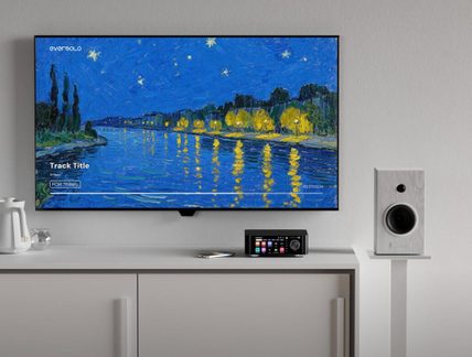 Black EverSolo network audio player with color display on TV stand between two modern white designer speakers