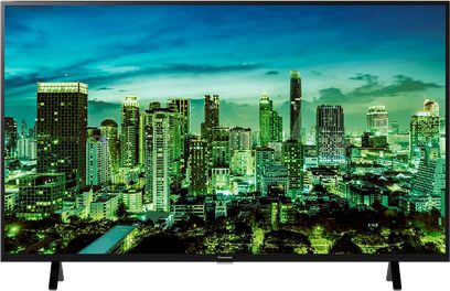 Panasonic TX-43LX700E-fladskærms-tv viser en oplyst by med moderne skyskrabere, set forfra mod en mørkeblå baggrund