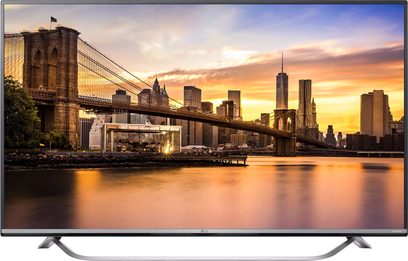 LG 49UF778V-fladskærm viser et panoramaudsigt over New York ved solnedgang med Brooklyn Bridge i forgrunden