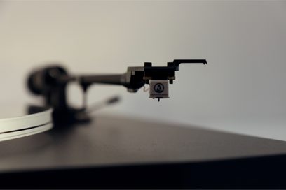 Tonarm til vinylpladespiller med monteret Audio-Technica pickup, tæt profilvisning på neutral grå baggrund