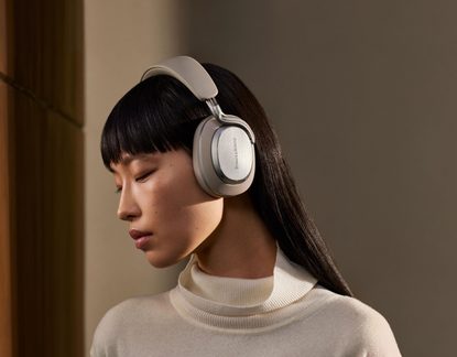 Sølvfarvede, circum-aurale hovedtelefoner med hus i børstet metal, polstret beige hovedbøjle, Bowers & Wilkins-logo, set fra venstre profil