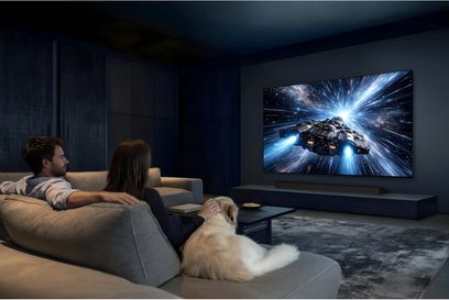 Televisore Samsung TQ77S95H grande schermo a parete in un soggiorno buio, vista di tre quarti con scena spaziale visualizzata