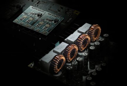 Audio amplifier circuit board with toroidal coils and black capacitors in close-up view