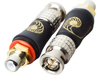 Close-up perspective view of two Cardas RCA/BNC cylindrical adapters, featuring a black flexible rubber body with a gold nautilus logo, knurled silver metal rings, and gold-plated contacts with white insulation.