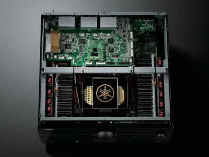 Zosilňovač domáceho kina Yamaha vnútorný pohľad so zelenými elektronickými doskami a centrálnym čierno-zlatým transformátorom