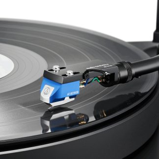 Mėlyna Audio-Technica AT-OC9XEB fonokasetė ant patefono tono rankenėlės iš arti, grojanti juodą vinilo plokštelę