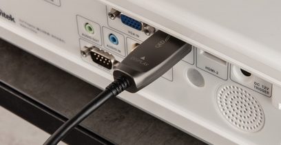 Câble HDMI QED Performance active optical 30m branché à un appareil avec ports HDMI, VGA, série et USB