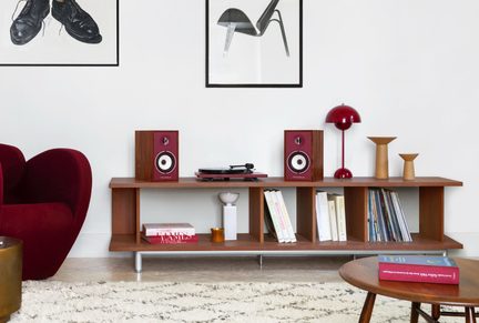 Lage houten kast, vooraanzicht, met platenspeler, twee bordeauxrode luidsprekers, rode lamp en een rij boeken en vazen