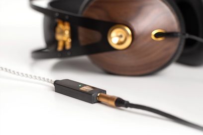 Draagbare iFi Audio GO Link audio-converter in donker hout, aangesloten op een zwarte kabel, naast een bruine koptelefoon