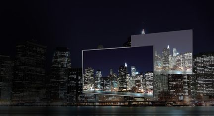 Illuminated skyscrapers at night in a large city, seen from across a body of water, with their reflection in the water