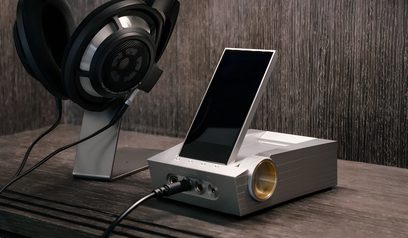 Wzmacniacz słuchawkowy Astell&Kern ACRO CA1000 z aluminiową, szczotkowaną obudową, wyświetlaczem, pokrętłem obrotowym i gniazdem jack, podłączony do czarnych słuchawek