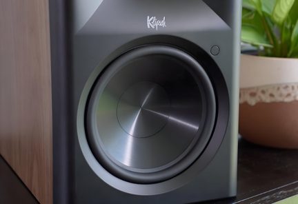 Schwarzer Klipsch-Subwoofer mit rundem Frontlautsprecher und seitlichem Paneel in Holzoptik