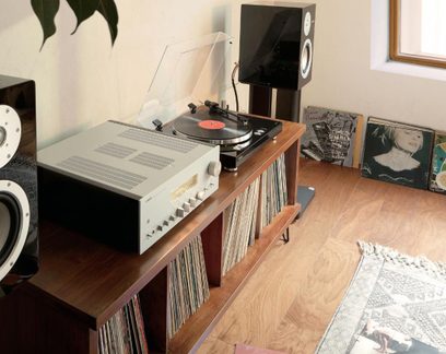 Hi-Fi-Plattenspieler auf Holzmöbel mit silbernem Yamaha-Verstärker, schwarzen Lautsprechern und einer Reihe von Schallplatten
