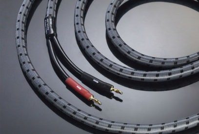 Nærbillede af sorte og røde Real Cable 3D-TDC 2x3 m lydkabler, set forfra, oprullet i spiral på ensfarvet grå baggrund