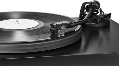 Juoda vinilinė patefonas Audio Technica AT-LP7X su juoda plokštele, balta etikete ir stambiu planu pavaizduotu tonarmu