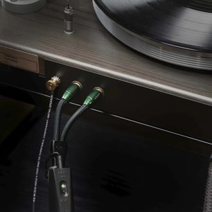 Audioquest Black Hole GroundGoody 5m audio kabel s phono konektory v zelené barvě připojený k gramofonu na dřevěném povrchu