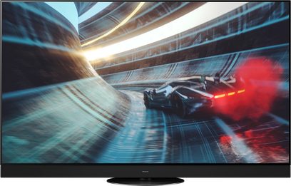 Téléviseur Panasonic TX-65MZ2000E affichant une scène de course automobile futuriste avec deux voitures rouges et noires filant à toute vitesse sur une route réfléchissante