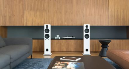 Paar weiße Standlautsprecher mit schwarzen Lautsprechern in einem modernen Wohnzimmer in Frontalansicht