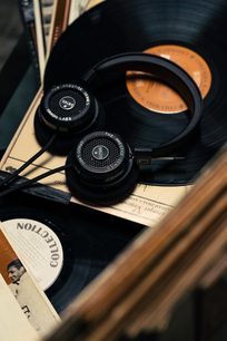 Åben Grado SR125x hi-fi hovedtelefon i sort, lagt på vinylplader, set ovenfra i nærbillede med brochure i forgrunden