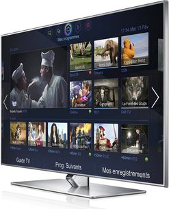 Samsung UE60F7000 fladskærms-TV, der viser en menu med miniaturebilleder af TV-programmer, set forfra på sort baggrund