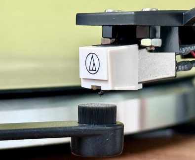 Cellule phono Audio-Technica blanche avec pointe de lecture, montée sur un porte-cellule noir, en gros plan