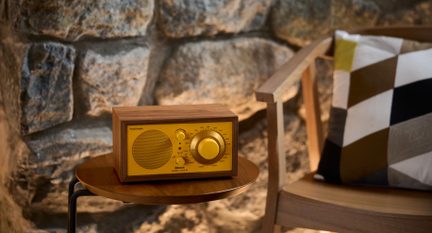Radio in legno da tavolo, frontale giallo, griglia circolare e grande pulsante rotativo a destra, vista da tre quarti anteriore