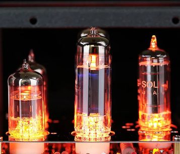 Nærbillede af tre elektronrør i gennemsigtigt glas oplyst af et orange skær, monteret lodret på kredsløbet i Cayin HA-1A MK2 high-fidelity hovedtelefonforforstærker
