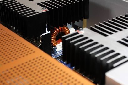 NAD M2 stereo hi-fi forstærker. Kobbertoroidal radiator mellem sorte køleplader. Blåt printplade. Sort gittergitter