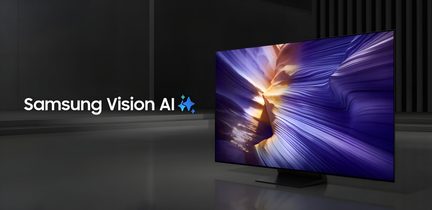 Televisore Samsung a schermo piatto nero opaco con cornice ultra-sottile in metallo e piedistallo centrale rettangolare, vista tre quarti anteriore destra, superficie dello schermo in vetro lucido che mostra motivi luminosi viola e dorati