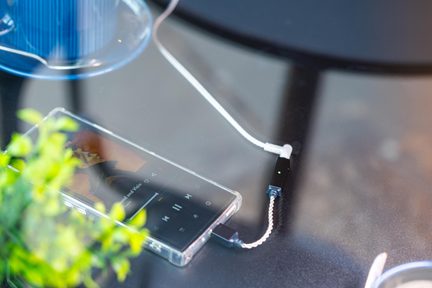 cam masanın üzerinde bir akıllı telefona bağlı siyah USB-C ses adaptörü, beyaz örgülü kablolu