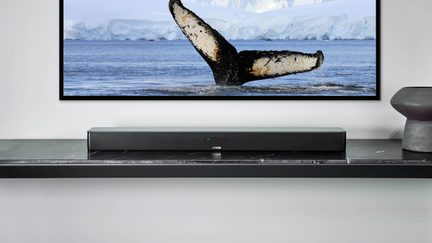 Zwarte Canton-soundbar op marmeren plank onder flatscreen-tv, walvisstaart in poolzee op het scherm