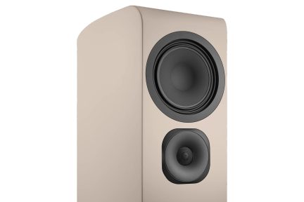 Beige bookshelf speaker shown in three-quarter view with large black woofer and black front tweeter