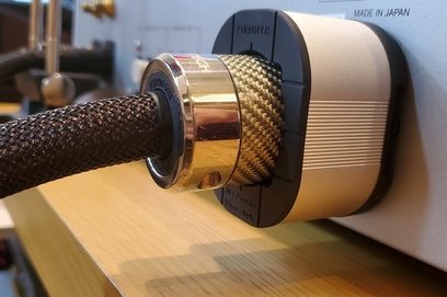 Furutech NCF Booster Brace Single, gull- og karbonfinish, nærbilde forfra, plassert på en tresoverflate