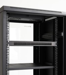 Fascia spazzola passacavi montata in un rack audiovisivo nero con griglie di ventilazione, supporti perforati e ripiani traforati
