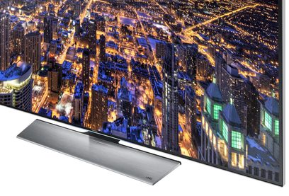 Samsung UE48HU7500 TV set set forfra, tændt skærm der viser en oplyst by om natten, smal sølvfarvet ramme