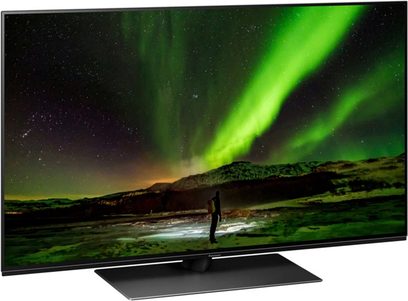 Panasonic TX-48JZ1500E-tv, der viser et grønt nordlys over et snedækket bjerglandskab med en menneskelig silhuet stående